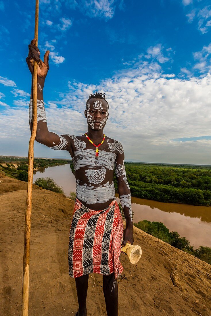 Kara Stammesmann mit kunstvoller Kreidemalerei auf seinem Körper, mit dem Omo Fluss im Hintergrund, Dus, Omo, Äthiopien