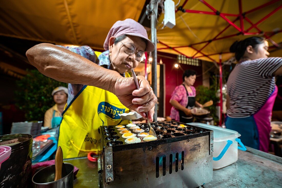 Stadt Krabi, Thailand, 23. November 2019, Wochenend-Nachtmarkt, ältere thailändische Frau bereitet Spiegeleier aus Vogeleiern vor
