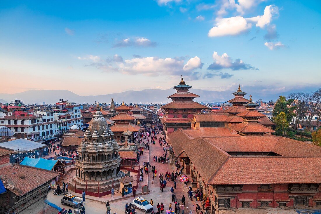 Kathmandu, Nepal - March 9 2020: Aerial view of Patan Durbar Square. People strolling around the temple premises. Pinncale of Temples and himalaya in the backdrop.