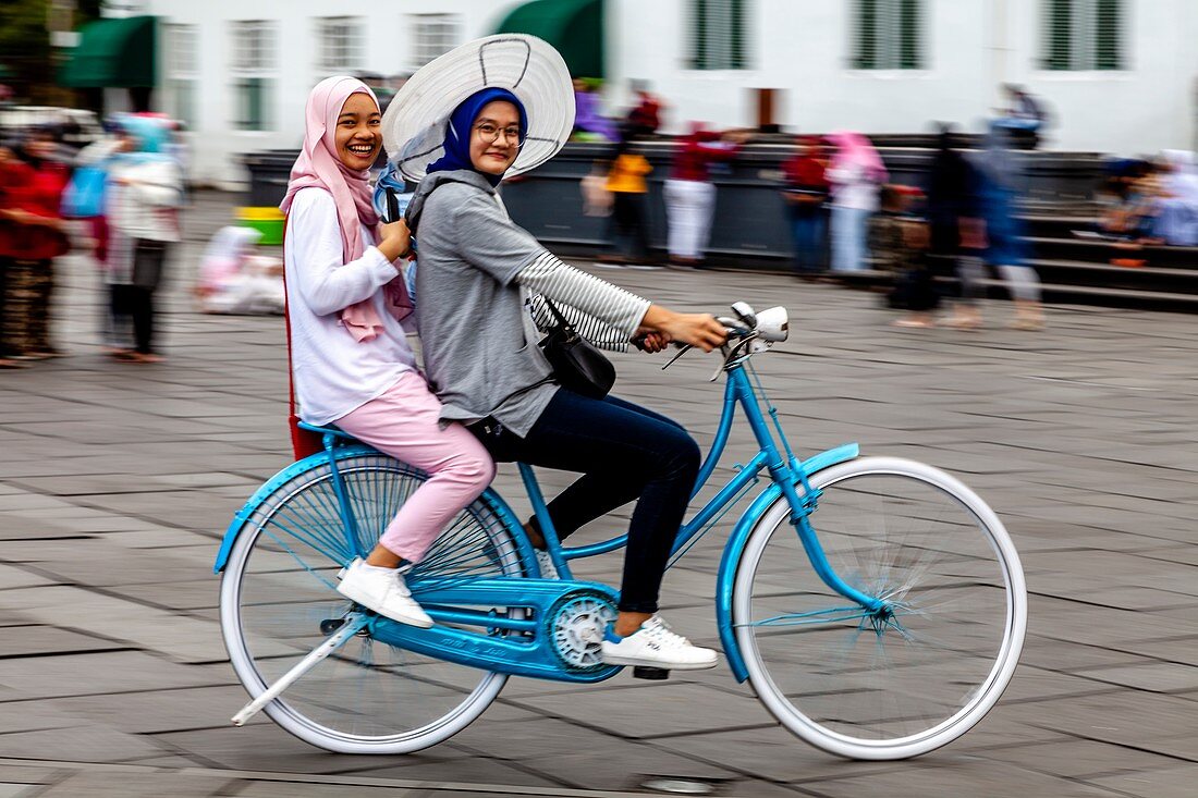 Junge indonesische Frauen radeln auf dem Taman Fatahillah-Platz, Jakarta, Indonesien