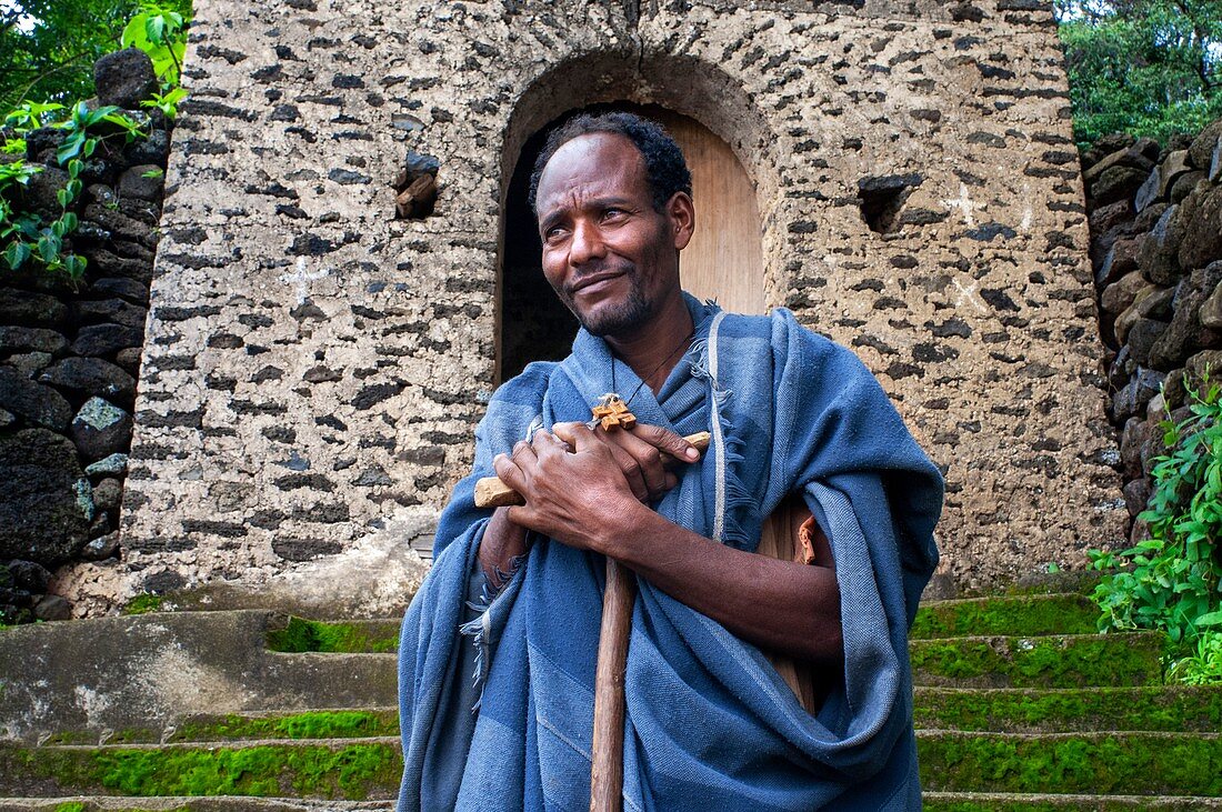 Debre-Sina-Beta-Maryam-Kirche, Lake Tana, Bahir Dar, Äthiopien. Ein Priester posiert majestätisch mit seinem Kreuz an der Tür des Birgida-Maryam-Klosters auf einer der Inseln des Tana-Sees. Der Tana-See, der größte See Äthiopiens, ist die Quelle des Blauen Nils, von wo aus er seine lange Reise nach Khartum und weiter ins Mittelmeer beginnt.