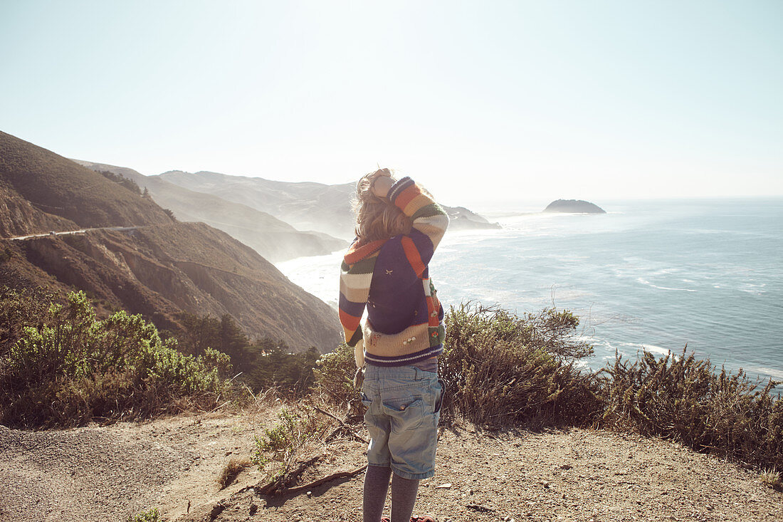 Child looks out over the Pacific Ocean and coast off Highway 1, Big Sur State Park, California, USA.