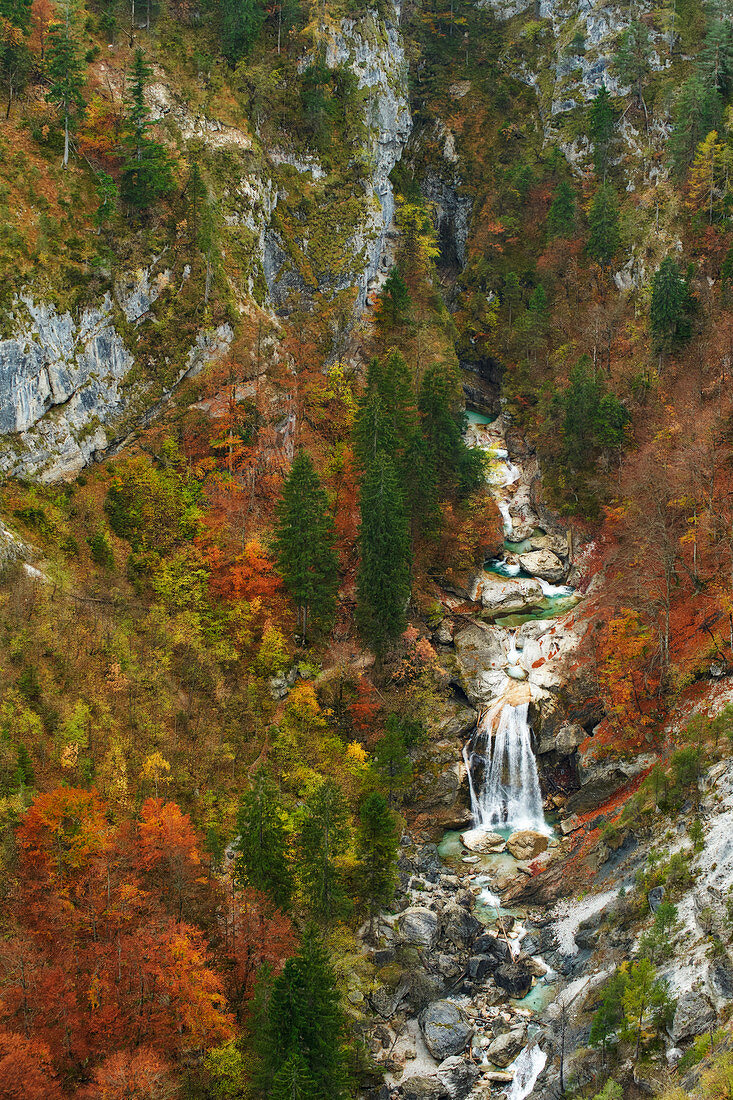 Blick von oben auf einen großen Wasserfall in der herbstlichen Garnitzenklamm, Kärnten, Österreich.