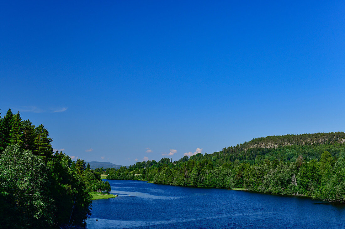 Blick auf einen blauen See mit Waldufer, bei Järvsö, Västernorrland, Schweden