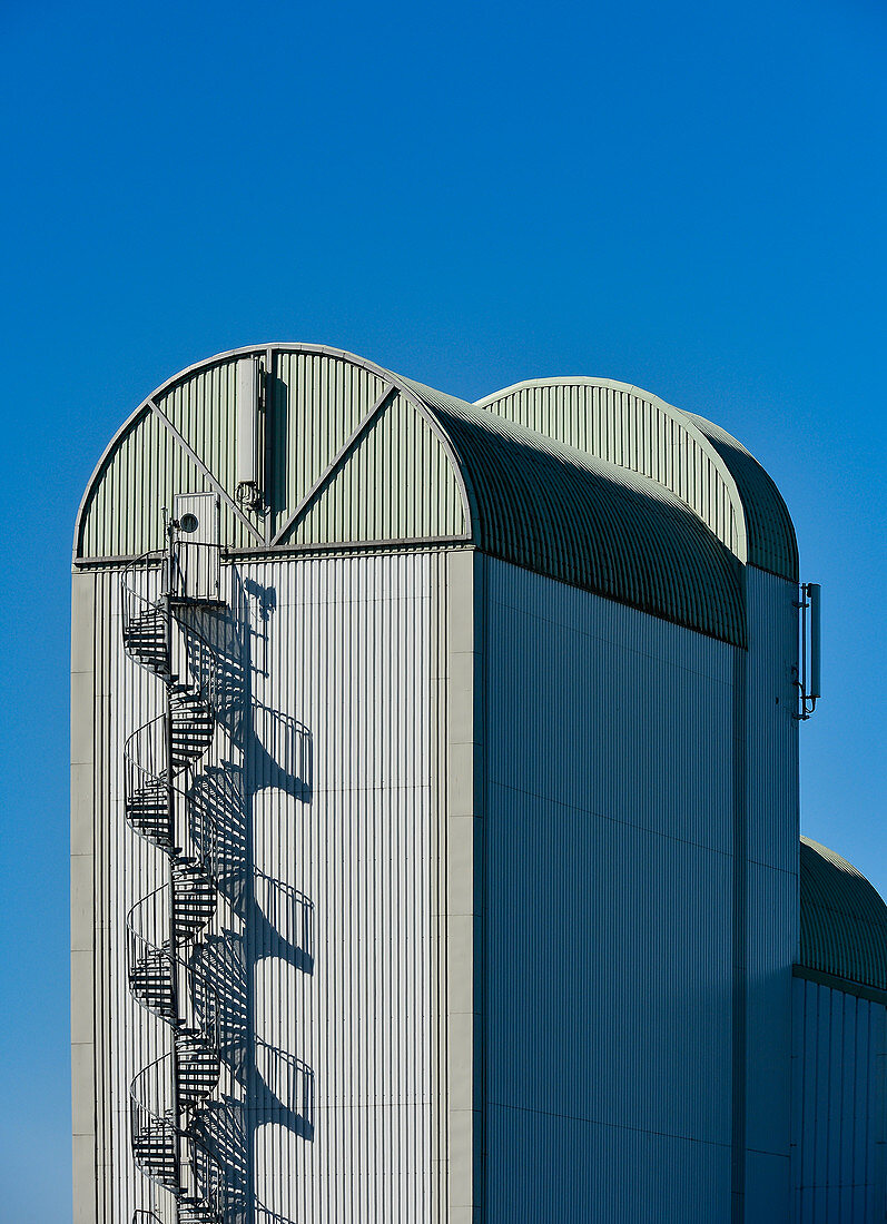 Grain elevator with spiral staircase against a deep blue sky in Skara, Sweden