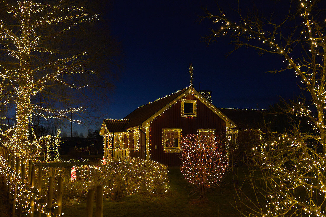 Wunderschöne Weihnachtsdekoration an Haus und Garten bei Nacht, Långaryd, Halland, Schweden