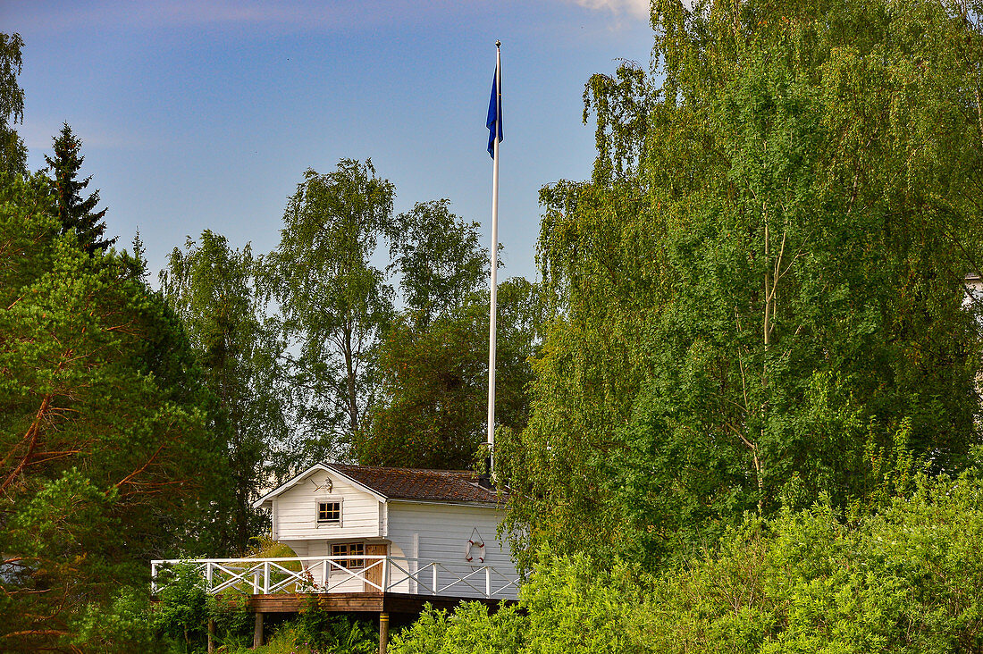 Small summer house with veranda and Swedish flag in the forest, Näs bruk, Avesta, Dalarna, Sweden