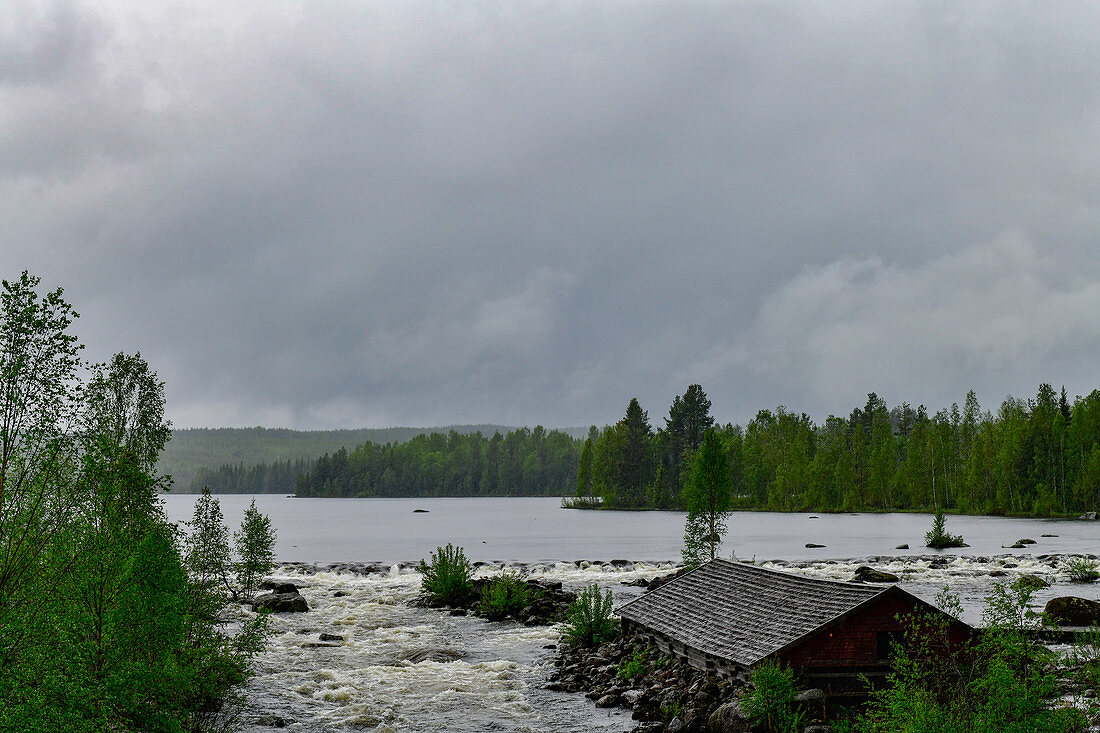 Lake and river with rapids and wooden hut in the forest, near Bräcke, Jämtland, Sweden
