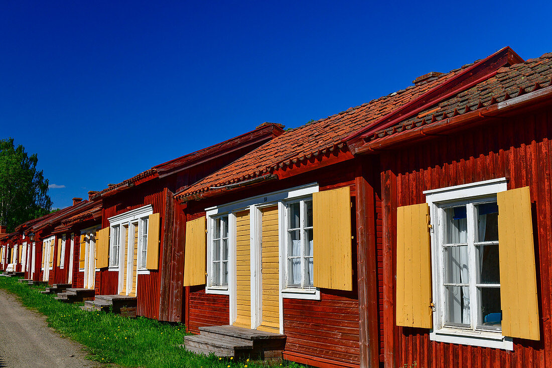 Reihe von roten Holzhütten mit gelben Fensterläden, Lövanger Kyrkstad, Västerbottens Län, Schweden