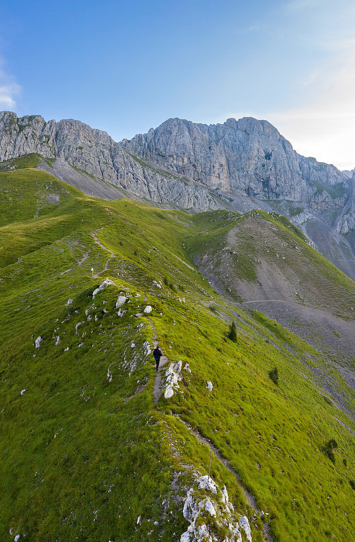 Blick von oben auf einen Mann, der im Morgengrauen am Passo degli Agnelli vor dem Pizzo della Presolana spazieren geht, Castione della Presolana, Provinz Bergamo, Serio-Tal, Lombardei, Italien