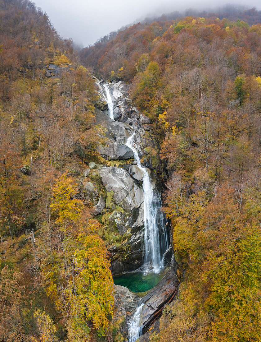 Luftaufnahme von dem Wasserfall des Flusses Valegg da Cansgell im Herbst nahe der Stadt Lavertezzo, Verzascatal, Kanton Tessin, Schweiz