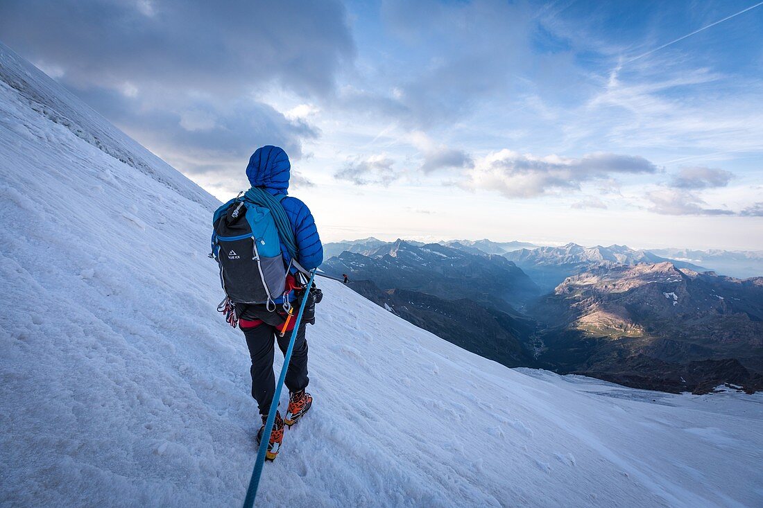 GUIDE LEADING HIS ROPED PARTY AT SUNRISE ON AN ICY SLOPE TO THE CASTOR, MONTE ROSA, GRESSONEY-LA-TRINITE, AOSTA VALLEY, ITALY