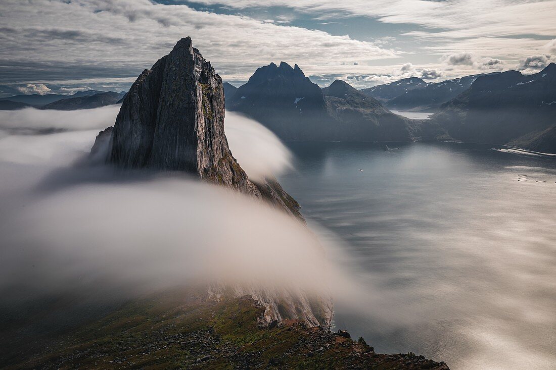 MOUNT SEGLA SURROUNDED BY CLOUDS PLUNGING INTO THE FJORD, FJORDGARD, SENJA, NORWAY