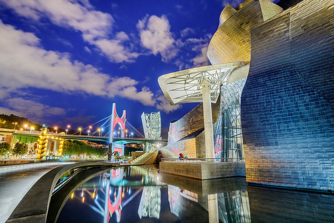 Beleuchtetes Guggenheim-Museum, Architekt Frank O. Gehry, mit Brücke Puente La Salve im Hintergrund, Bilbao, Baskenland, Spanien