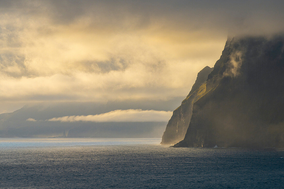 Steilküste im Westen der Insel Vágar mit dem Wasserfall Bøsdalafossur und der Felsnadel Geitaskoradrangur, Färöer Inseln, Dänemark