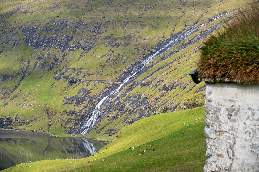 Wasserfall mit einem grasbewachsenem Dach im Vordergrund, Saksun, Insel Streymoy auf den Färöer Inseln
