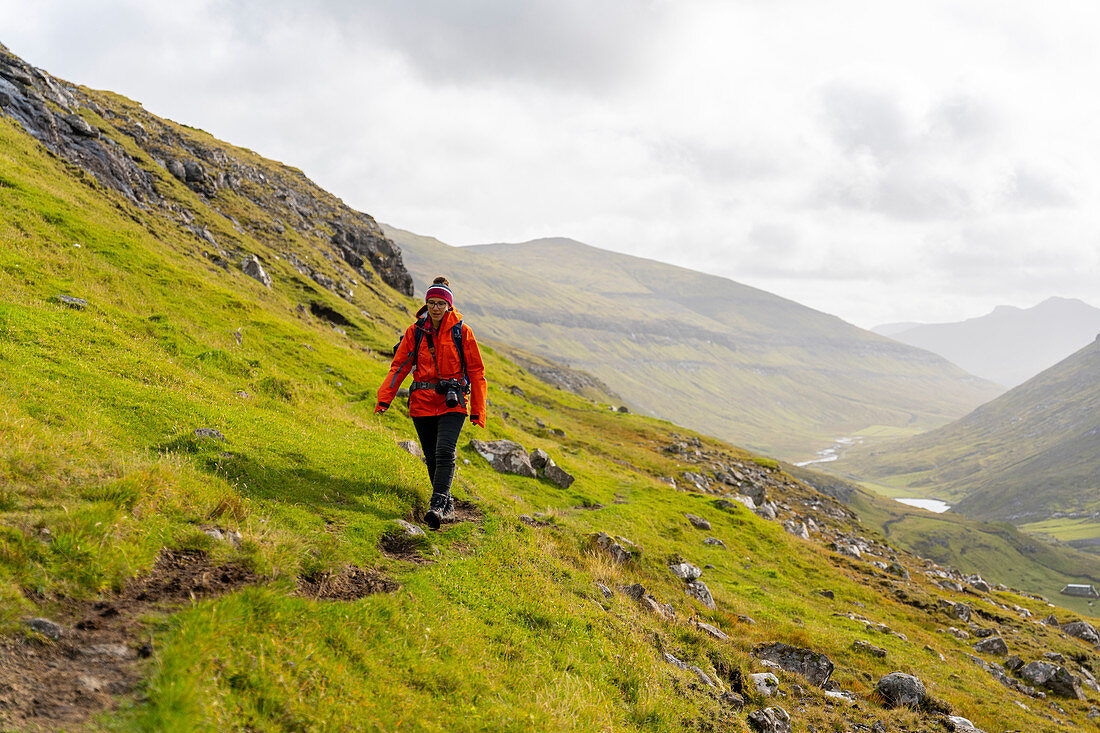 Photographer walks through the grassy mountain landscape between Saksun and Tjørnuvík, Streymoy, Faroe Islands