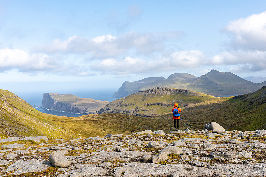Photographer walks through the grassy mountain landscape between Saksun and Tjørnuvík, looking at Tjørnuvík, Streymoy, Faroe Islands