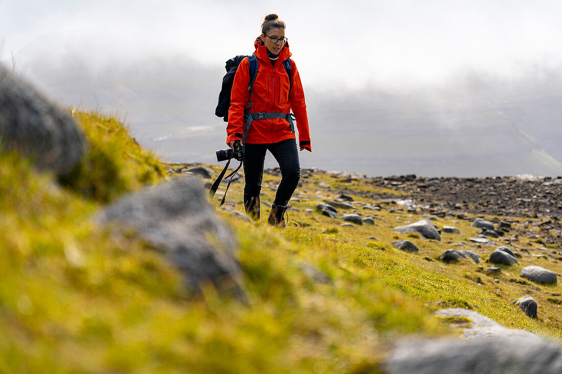 Fotografin wandert durch die grasbewachsene Berglandschaft zwischen Saksun und Tjørnuvík, Streymoy, Färöer Inseln
