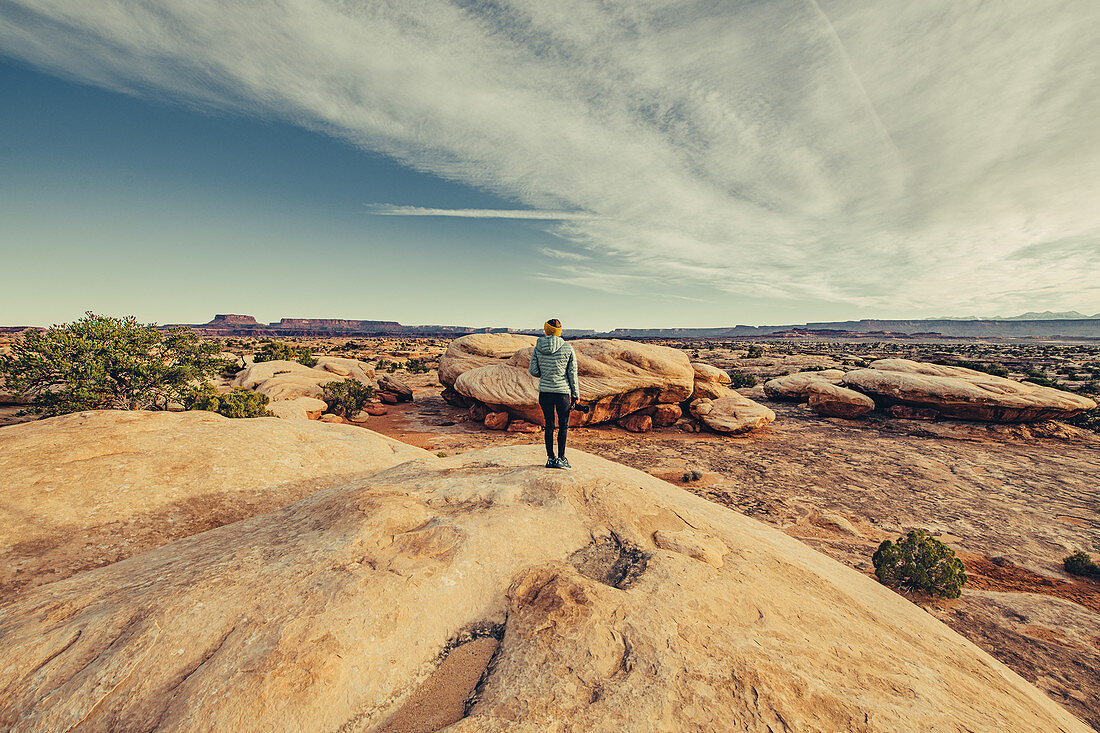 Woman with camera standing on rock in Canyonlands National Park; Utah, USA, North America