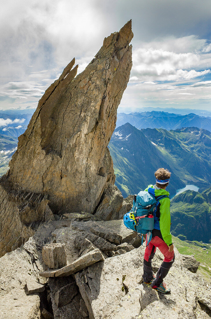 Hiker beside the rock pinnacle on eastern crest of Pizzo Andolla, between Loranco valley (Ossola) and Zwischbergental, (Switzerland)