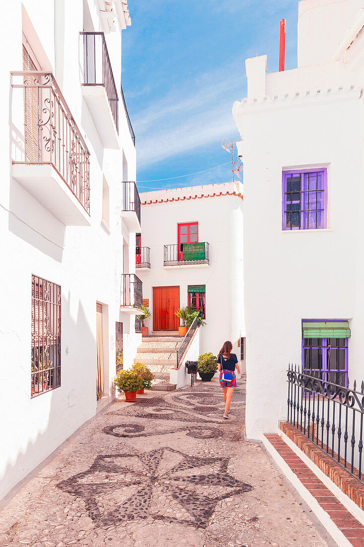 Frau spaziert auf der Straße mit typisch maurischen Kopfsteinpflastern in Frigiliana, La Axarquia, Provinz Malaga, Andalusien, Spanien, Europa