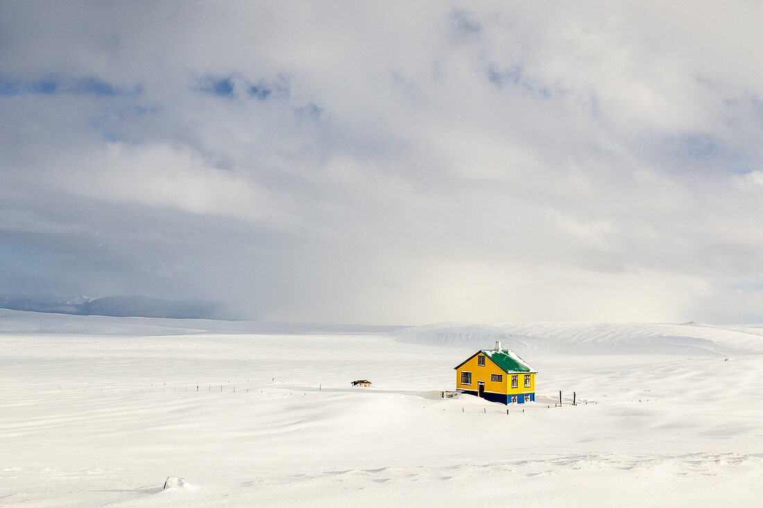 Island, Westisland, Halbinsel Snaefellsness, ein einsames, farbenfrohes Haus auf einem schneebedeckten Feld