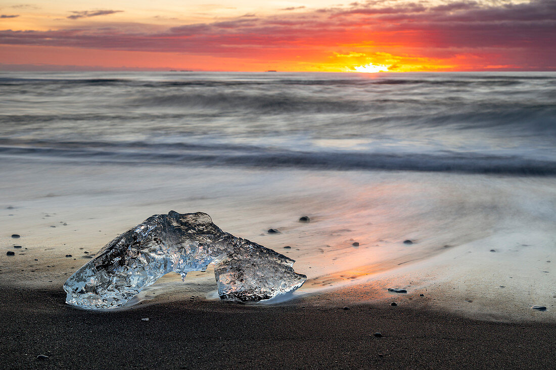 Island, Südisland, Jökulsárlón, Eisberg am schwarzen Sandstrand bei Sonnenaufgang