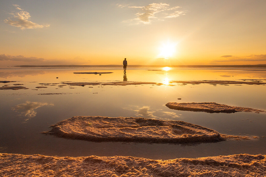 A tourist admiring sunset along the beach of Tuz Golu salt lake. Sereflikochisar, Ankara district, central Anatolia, Turkey.