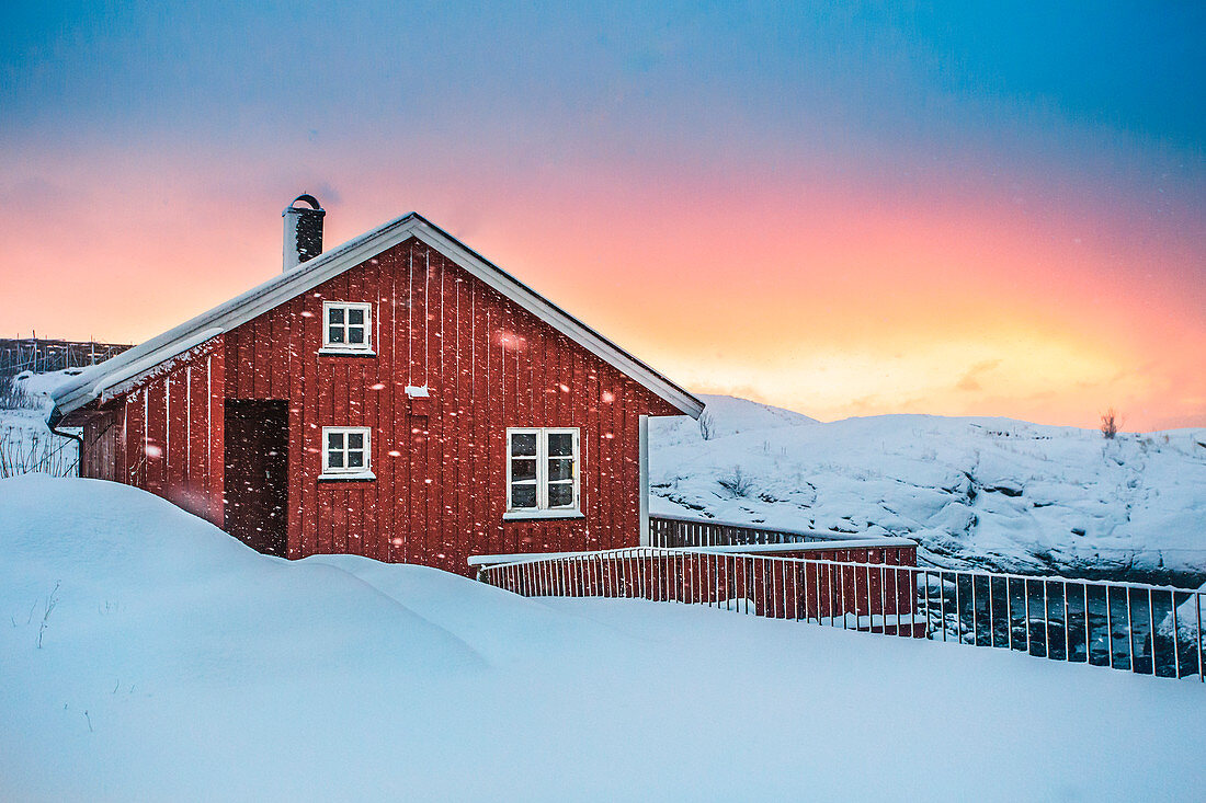 Typisches rotes Haus spiegelt sich im Meer, Reine, Lofoten, Nordnorwegen