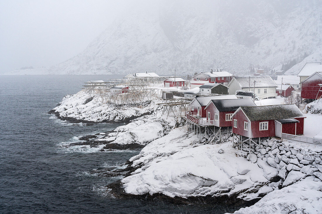 Nahaufnahme des Dorfes Hamnoy im Schnee, mit dem Berg Festheltinden im Hintergrund, Moskenes, Nordland, Nordnorwegen, Norwegen