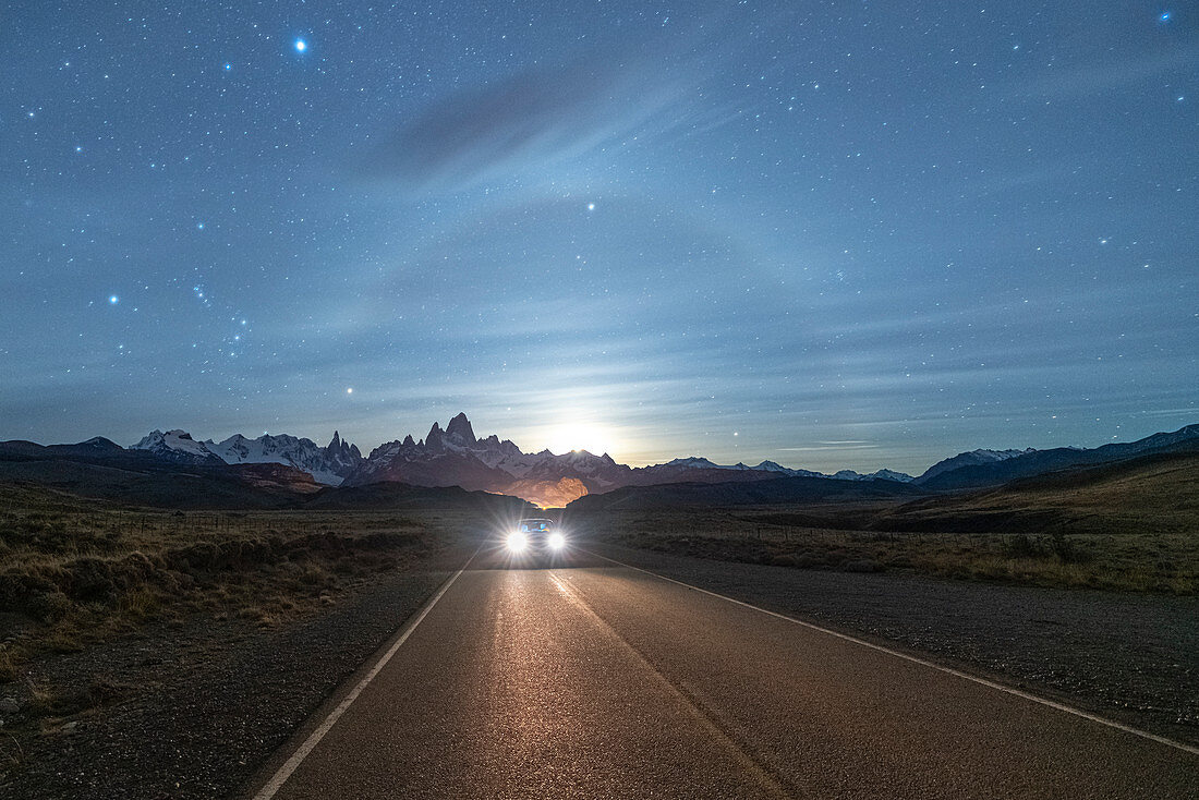 Autofahren auf der Straße nach El Chalten, nachts mit Fitz Roy Gebirge und Mondlicht im Hintergrund, El Chalten, Provinz Santa Cruz, Argentinien