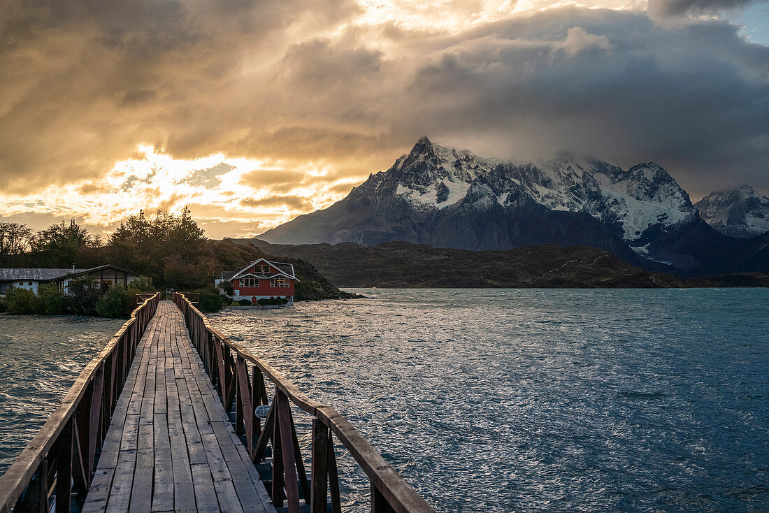 Wooden bridge on Lake Pehoé with Cerro Paine Grande in the background at sunset. Torres del Paine National Park, Ultima Esperanza province, Chile.