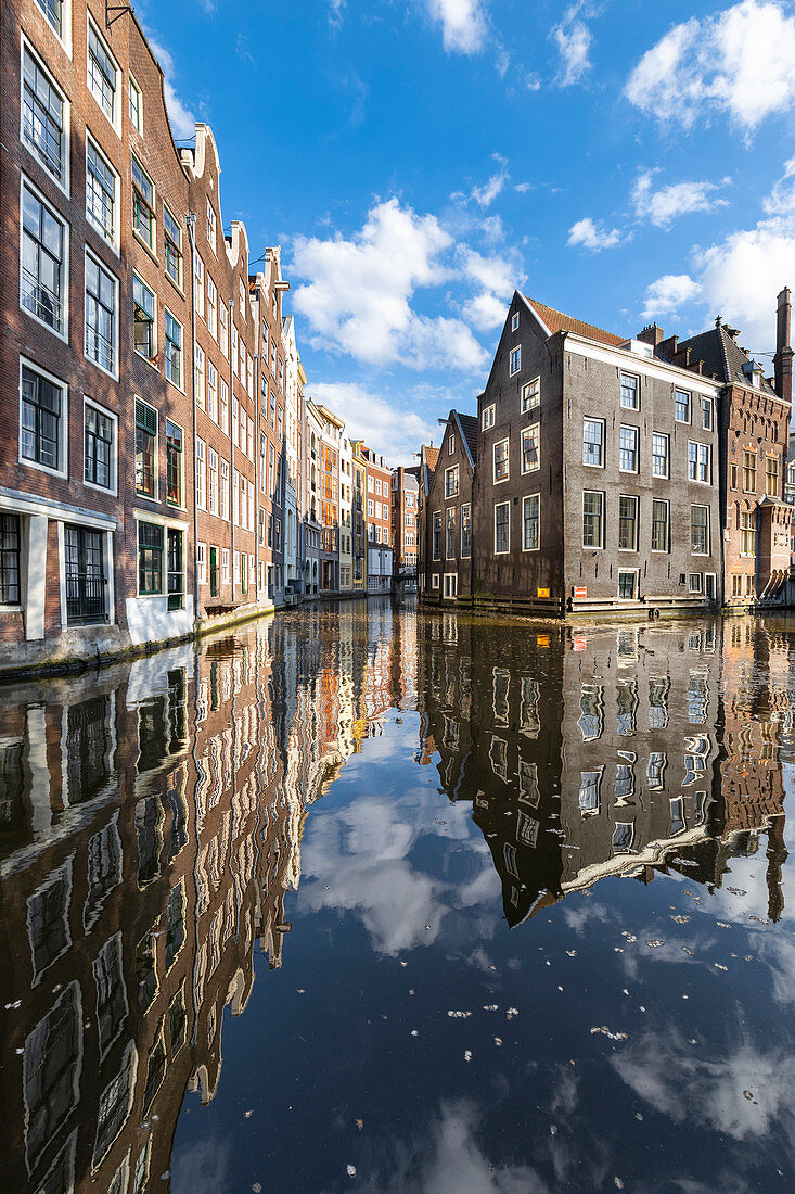 Typical houses reflected on canals in De Wallen district in Amsterdam (North Holland, Netherlands)