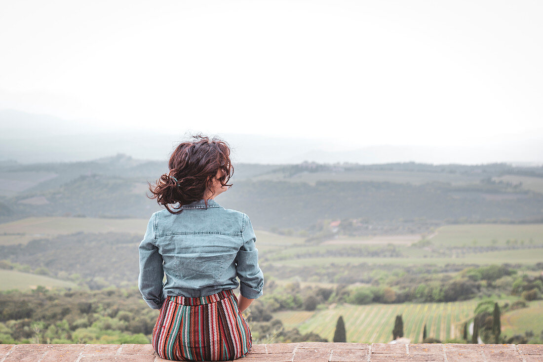 Ein Mädchen beobachtet die Landschaft von Sant'Angelo in Colle, Siena, Toskana, Italien, Europa