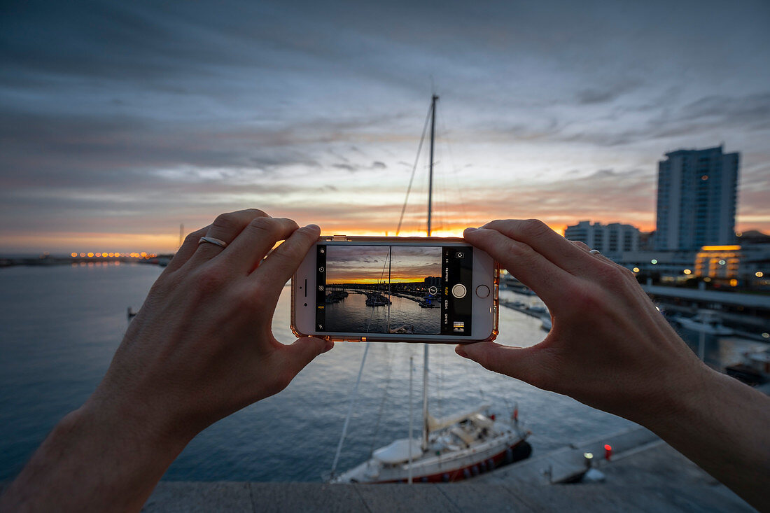A man photographs the pier of Ponta Delgada Marina at sunset , Ponta Delgada, Sao Miguel, Azores, Portugal, Western Europe 