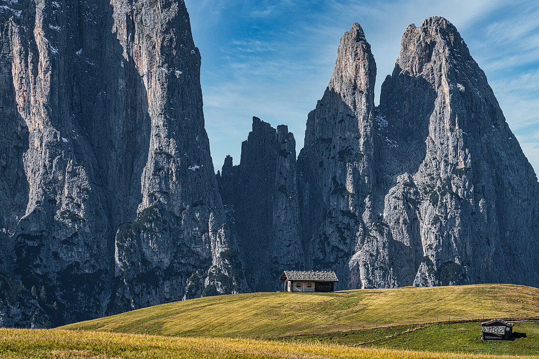 Huts in front of a massive mountain wall on the Seiser Alm in South Tyrol, Italy