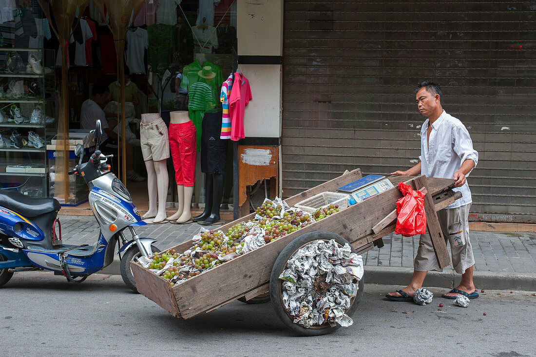 Ein Mann mit einem Wagen verkauft Trauben in der ehemaligen jüdischen Nachbarschaft in der Tilanqiao historischen Gegend des Hongkou-Bezirks von Shanghai, China.