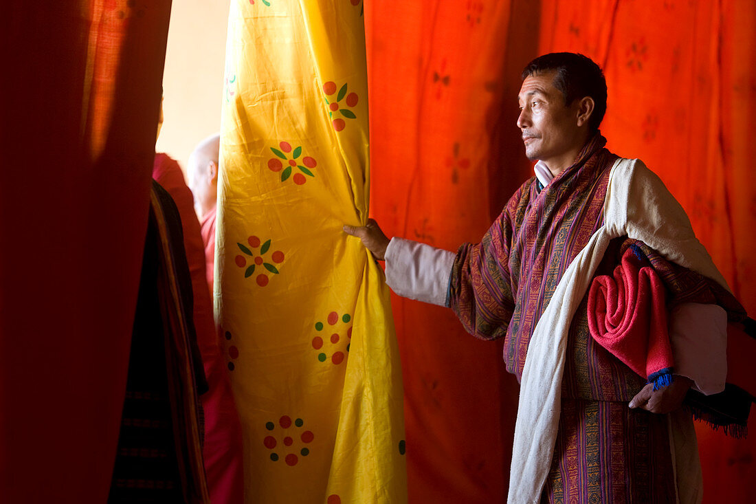 Mann beobachtet durch Vorhänge die Aufführung, Festival, Trashichhoe Dzong (Kloster), Thimpu, Bhutan