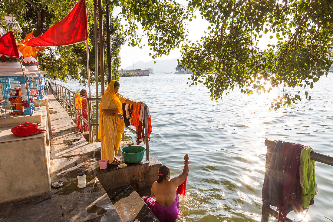 Women bathing & washing clothes in Pichola Lake at sunset, Udaipur, Rajasthan, India