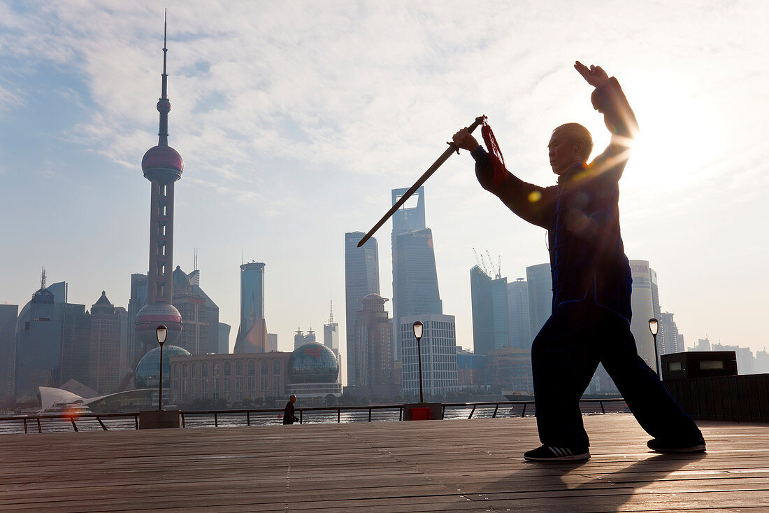 Üben von Tai Chi mit dem Schwert, mit Pudong-Skyline, früher Morgen, Shanghai, China