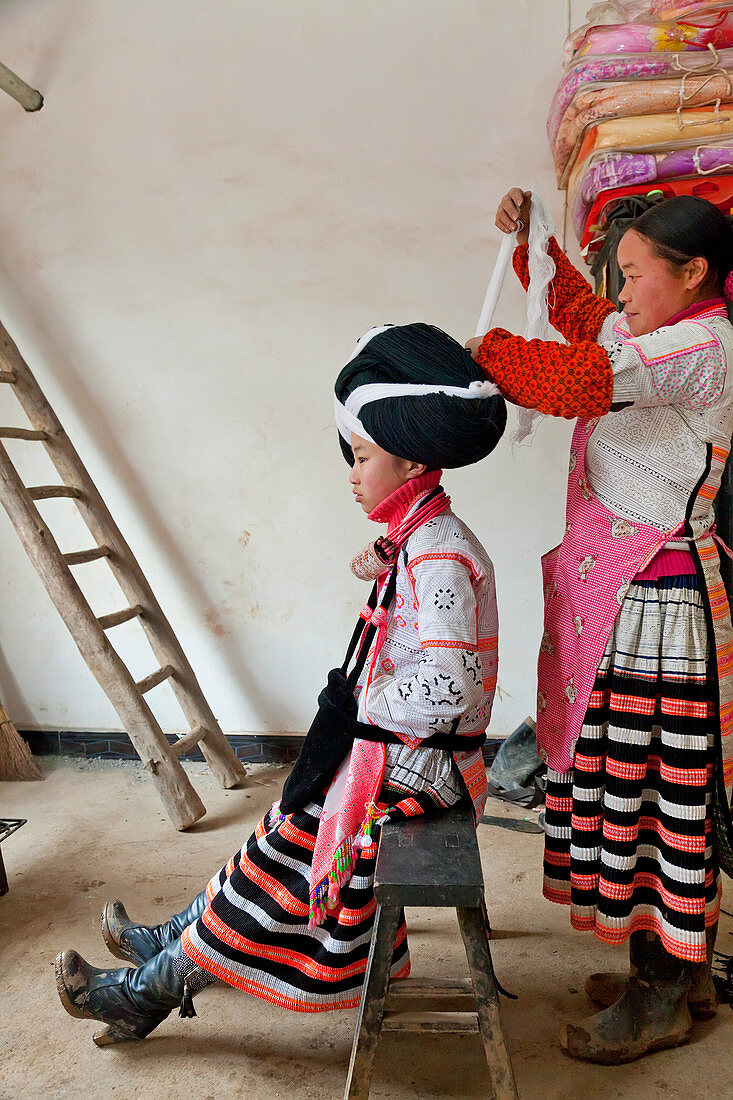 Long Horn Miao woman preparing the headdress of a girl, Sugao, China