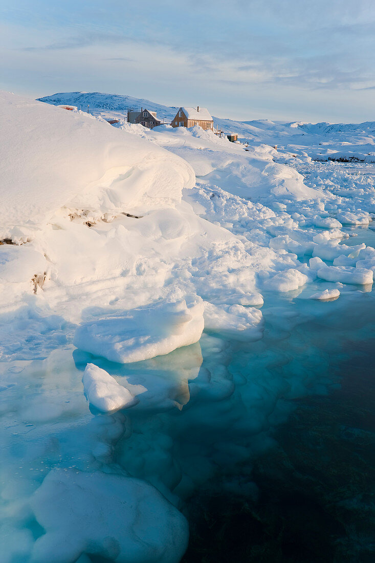 Tiniteqilaq-Haus am Rande eines Fjords mit Meereis, Grönland