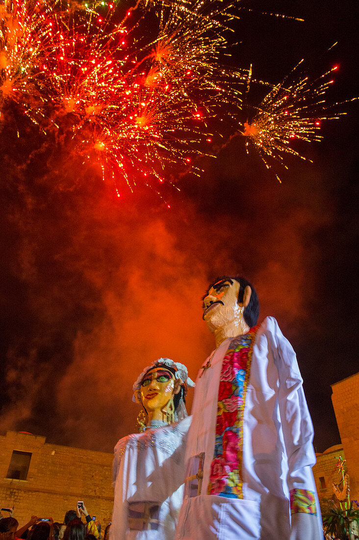 Feuerwerk und Riesenpuppen, gekleidet als Braut und Bräutigam während einer Calenda, einer Prozession durch die Straßen der Innenstadt von Oaxaca, die eine Hochzeit in der Stadt Oaxaca de Juarez, Oaxaca, Mexiko feiert.