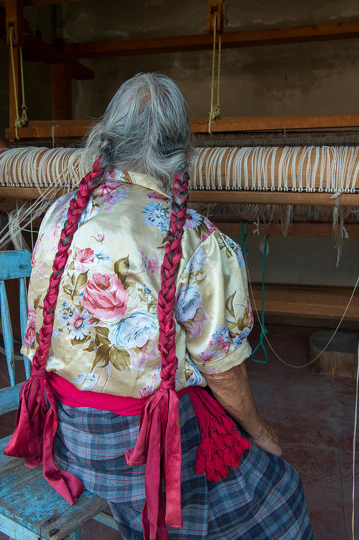 An old Zapotek woman is preparing a loom for weaving a carpet at a weavers home studio in Teotitlan del Valle, a small town in the Valles Centrales Region near Oaxaca, southern Mexico.