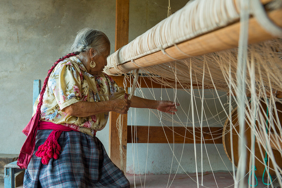Eine alte Zapotek-Frau bereitet einen Webstuhl für das Weben eines Teppichs in einem Heimstudio für Weber in Teotitlan del Valle vor, einer kleinen Stadt in der Region Valles Centrales in der Nähe von Oaxaca im Süden Mexikos.