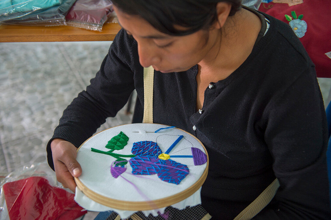 Eine mexikanische Frau stickt in einer Nähwerkstatt und zeigt, wie man einen Handwerksbetrieb einrichtet, der von US-Frauen im mixtekischen Dorf San Juan Contreras in der Nähe von Oaxaca, Mexiko, unterrichtet wird.