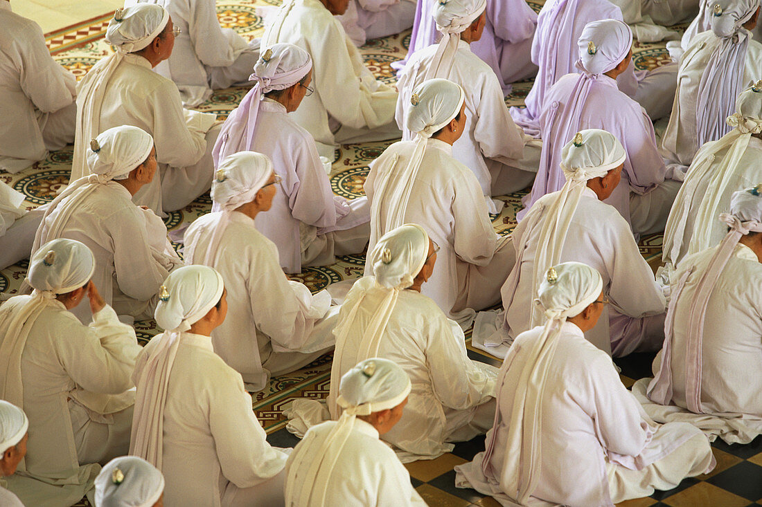Women praying at Cao Dai Temple, Tay Ninh Vietnam