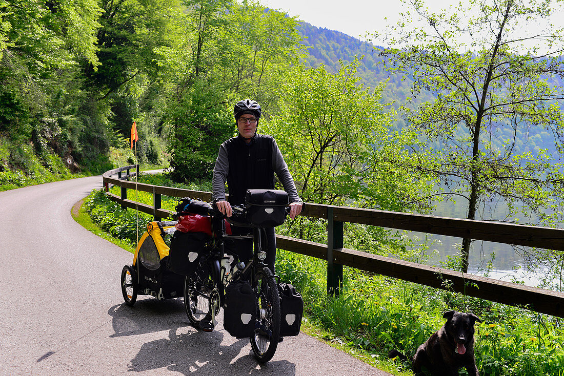 Radfahrer mit vollbepacktem Fahrrad und Hund am Donauradweg, Schlögen, Österreich