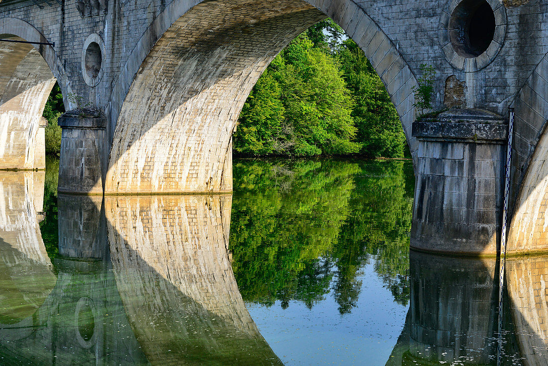 An old stone bridge and water reflection on the Moselle near Liverdun, France